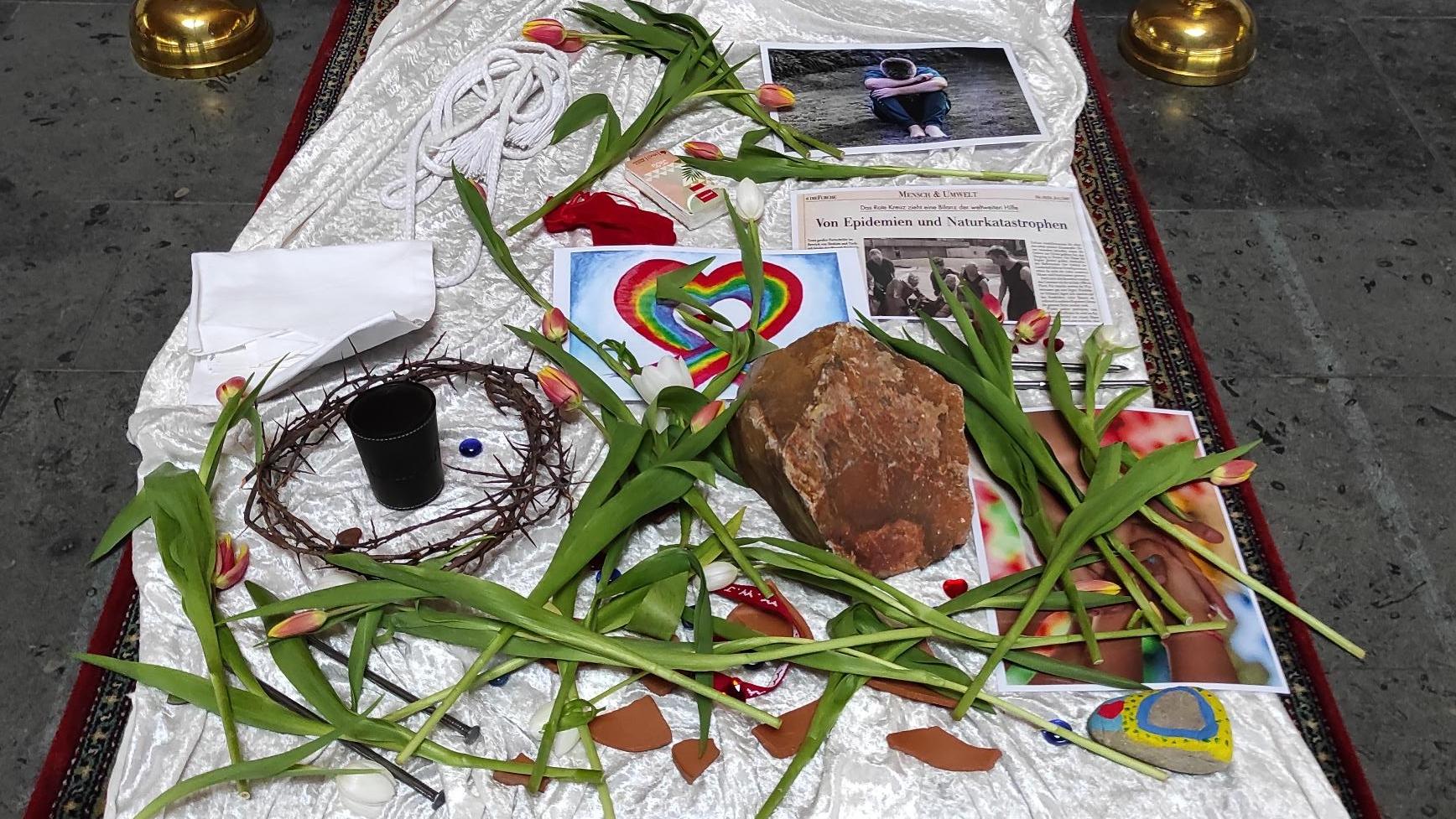 Symbole und Blumen vorm Kreuz