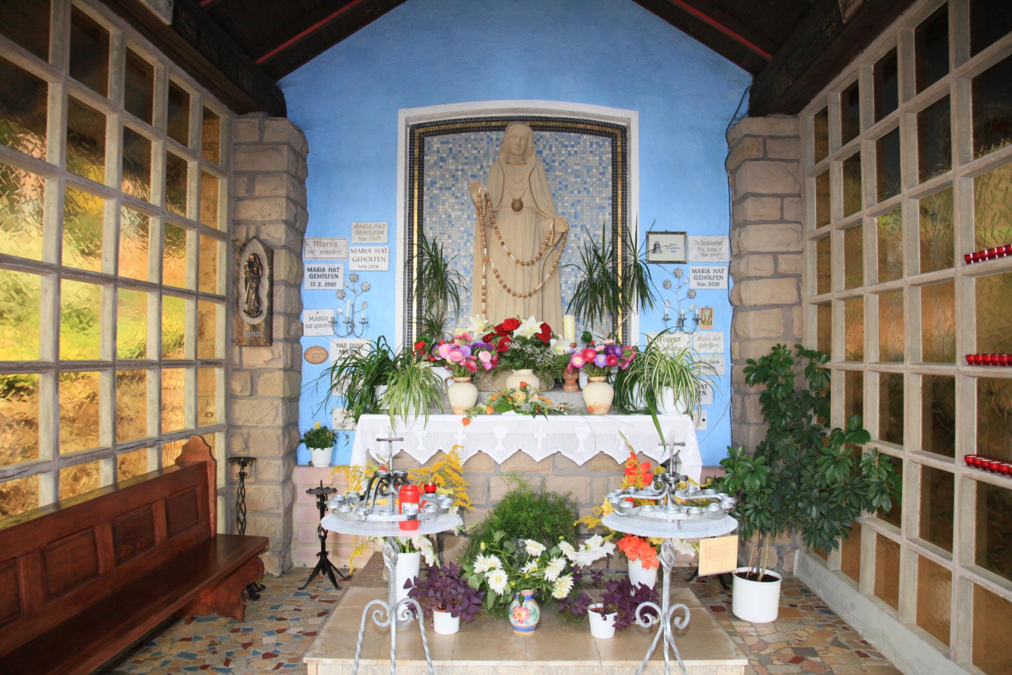 Statue von Maria mit Blumen und Kerzen